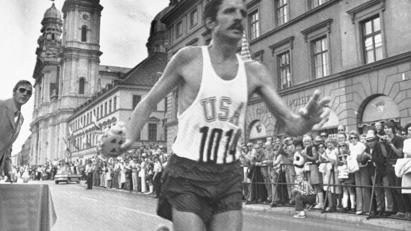 American Frank Shorter grabs a drink from a table while running through Munich in the 1972 Olympic marathon, which he won.
